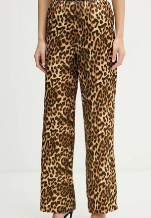 Donna che indossa pantaloni a vita alta e taglio largo con motivo leopardato marrone e nero, in piedi con le mani rilassate ai lati.