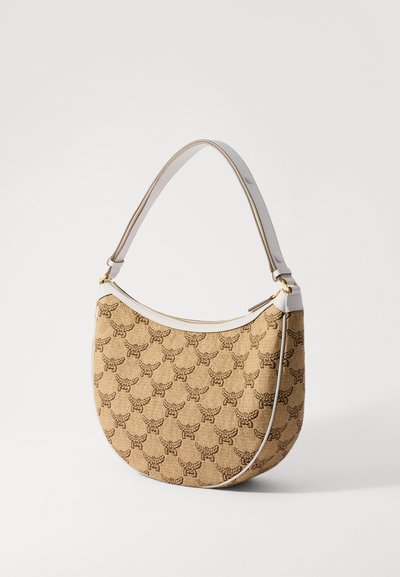 Beige félhold alakú kézitáska barna méh mintával, fehér bőr részletekkel és állítható vállpánttal, fehér háttér előtt bemutatva.