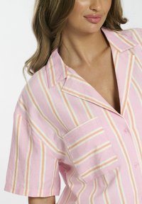 Pink striped short-sleeve shirt featuring light orange and white stripes, a collar, and a front pocket with a button detail.