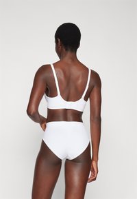 White bra and high-waisted underwear set, made from smooth fabric. Features adjustable straps and a seamless design without visible hardware.