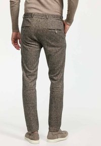 Grau gestreifte Hose aus strukturiertem Stoff, mit schmalem Schnitt, Gesäßtaschen und dezenten metallischen Akzenten, kombiniert mit hellgrauen Schuhen.