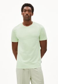 Lichtgroene katoenen T-shirt met ronde hals en korte mouwen. De stof lijkt glad en zacht, met minimale stikdetails.