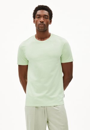 T-shirt in cotone verde chiaro con collo rotondo e maniche corte. Il tessuto appare liscio e morbido, con dettagli di cucitura minimi.