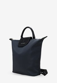 Bolsa de tote negra de nailon con acentos de cuero negro texturizado, asas superiores y solapa plegable. Presenta un diseño elegante y minimalista.