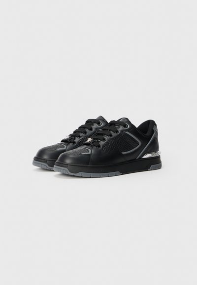Black sneakers with a textured leather upper, gray sole, decorative accents, and patterned design on the toe and sides.