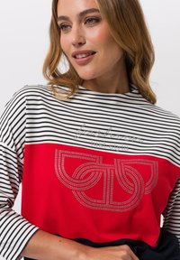 Langärmliges Oberteil mit roten und weißen Streifen, das mit Kristallverzierungen in einem Logodesign versehen ist, mit rundem Ausschnitt und lockerem Schnitt.