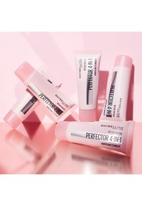 Tubi Maybelline Perfector 4-in-1 in tonalità rosa e bianco, con una finitura opaca liscia e un design elegante, disposti su una superficie riflettente.