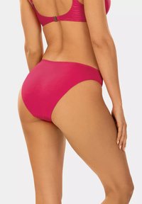 Fuksjowe bikini dolne o gładkiej fakturze oraz wysokim kroju, prezentujące bezszwowe dopasowanie i minimalne zakrycie, pokazane z widoku z tyłu.