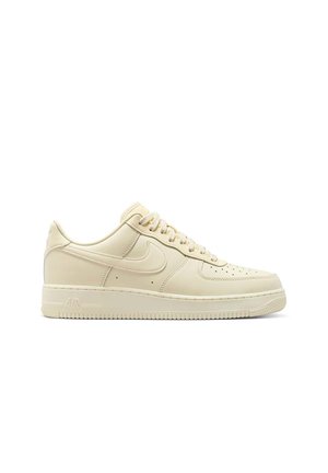 Sneaker Nike Air Force 1 beige a bassa altezza con lacci, punta perforata e suola in gomma su sfondo bianco.