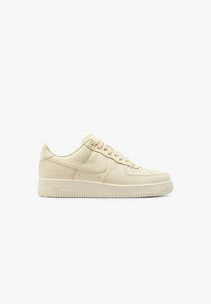 Sneaker Nike Air Force 1 beige a bassa altezza con lacci, punta perforata e suola in gomma su sfondo bianco.