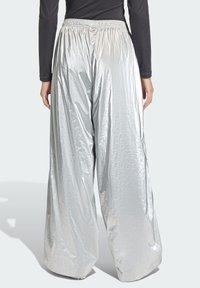 Ασημένιο μεταλλικό παντελόνι με φαρδιά γραμμή, με λεία, γυαλιστερή υφή και ελαστική μέση, που παρουσιάζει ένα χαλαρό, άνετο σχέδιο.