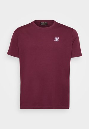 Bordeaux Baumwoll-T-Shirt mit runder Halslinie, kurzen Ärmeln und einem kleinen weißen Logo auf der linken Brust. Glatte Textur und klassischer Schnitt.