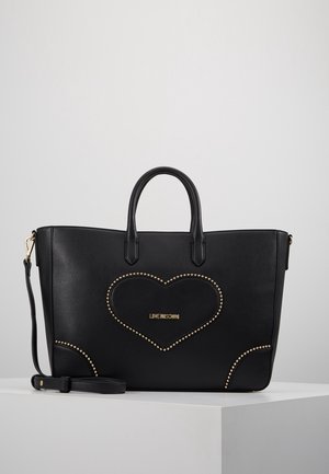 Czarna skórzana torba typu tote z podwójnymi uchwytami, odpinanym paskiem na ramię, ozdobą w kształcie serca z nitami oraz logo "LOVE MOSCHINO" na przodzie.