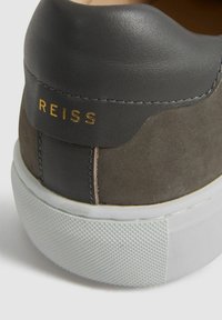 Tenis gri din suede și piele, cu talpă din cauciuc alb, având branding-ul auriu "REISS" pe toc și accente texturate pe talpă.