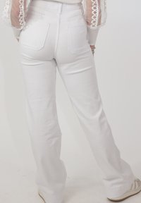 Hvide højtaljede, vidde jeans med baglommer, glat tekstur og et rent design. Bruges med lyse sneakers.