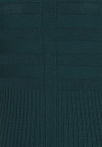 Pull texturé coloris sarcelle, avec côtes verticales et motifs à rayures horizontales. Maille douce avec une coupe ajustée et un léger éclat.