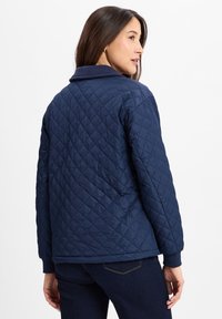 Navy gesteppte Jacke mit Stehkragen, mit diagonalen Rautenmuster und gerippten Bündchen. Glatte Textur, leichtes Design.