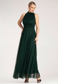 Długa zielona sukienka na ramiączkach, dopasowany gorset i lejąca spódnica. Posiada przezroczyste boczne panele oraz miękką fakturę tkaniny.