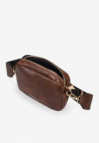 Bolso de cuero marrón tipo bandolera con forma rectangular, cremallera dorada y correa ajustable con patrón. Logo visible en la parte frontal.