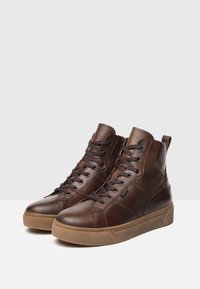 Sneaker alte in pelle marrone con finitura texturizzata, dotate di lacci tondi, occhielli metallici e suola in gomma.