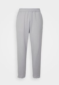 Ljusgrå sweatshirtbyxor med elastisk midja, avslutade ärmar och sidfickor. Har en liten vit logotyp på vänster ben.