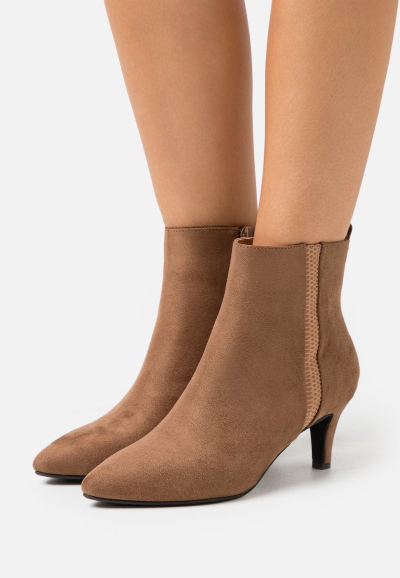 Bottes courtes en daim brun avec un bout pointu, un petit talon kitten bas et un détail de panneau latéral texturé.