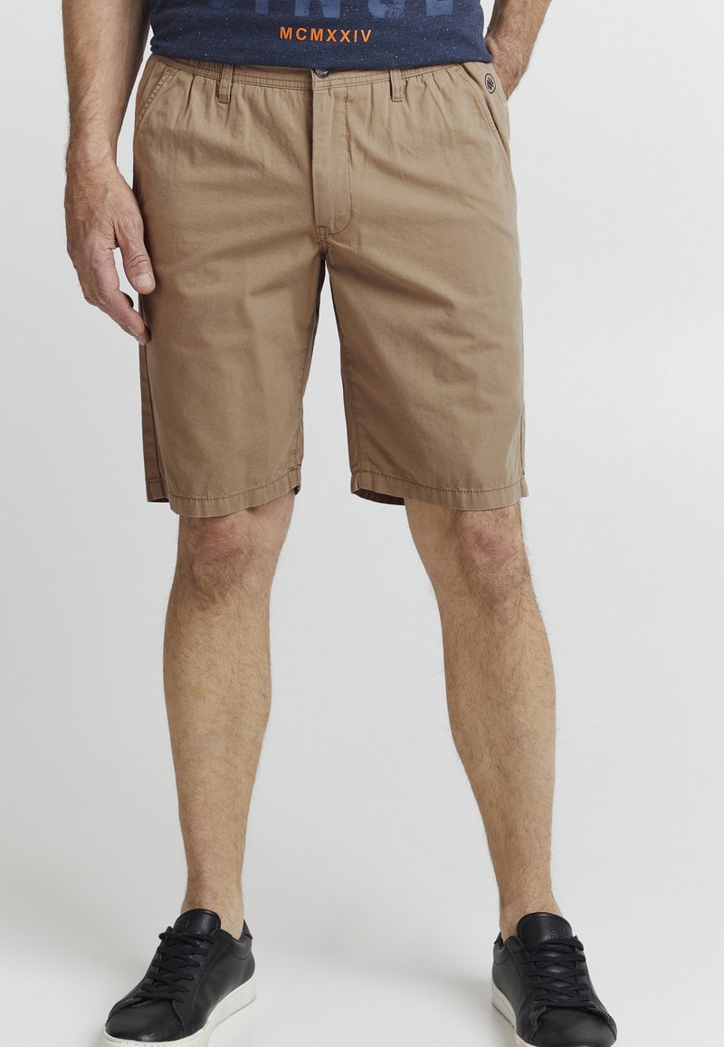 Kaki shorts laget av lett materiale, med avslappet passform, sidelommer og rett kant. Kombinert med svarte sneakers.