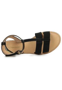 Sandale noire avec deux larges sangles élastiques, une sangle circulaire pour la cheville et une semelle intérieure en cuir naturel. Semelle plate avec des coutures détaillées.