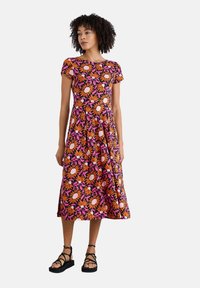 Floral dress with short sleeves; features orange, pink, and purple flowers on a black background; flared skirt; worn with black strappy sandals.