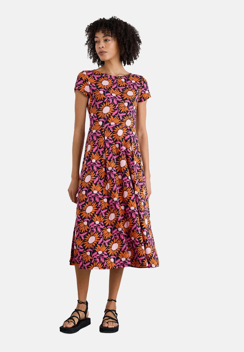 Floral dress with short sleeves; features orange, pink, and purple flowers on a black background; flared skirt; worn with black strappy sandals.