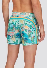 Costumi da bagno con una vivace stampa tropicale in acqua, caratterizzati da una striscia laterale gialla e due tasche posteriori con dettagli di branding.