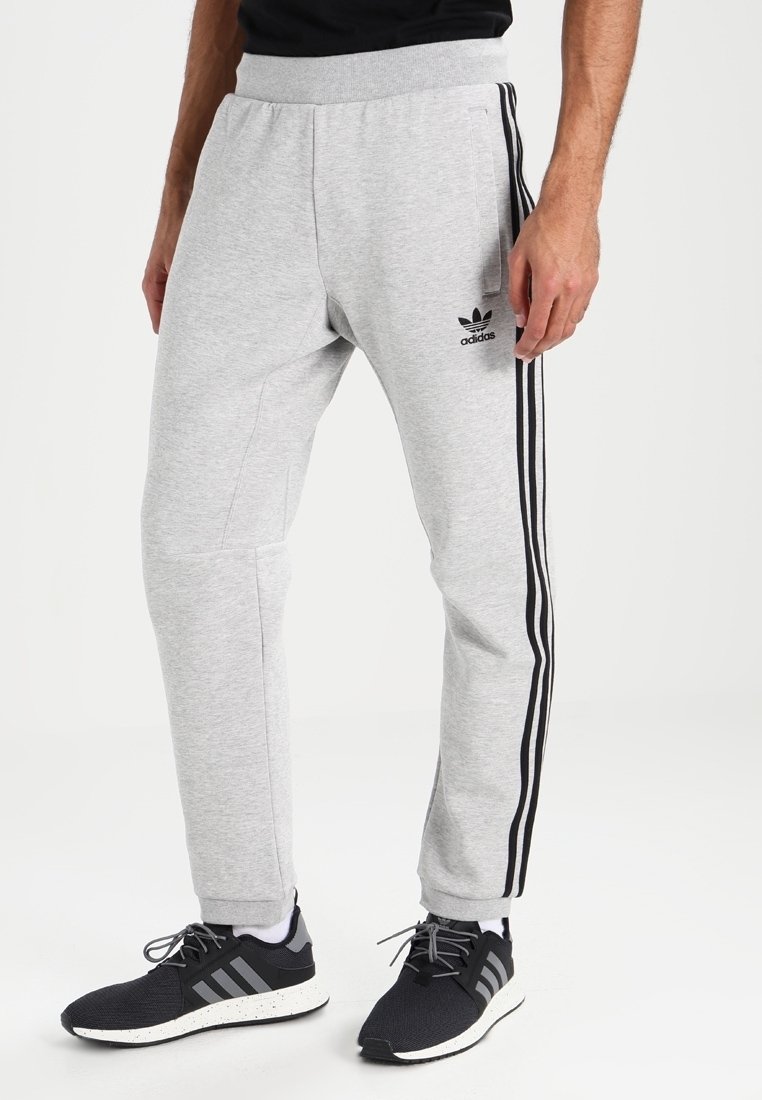 Grå sweatpants i mjukt material, med en avsmalnande design, svarta sidorand och en broderad logotyp på vänster lår.
