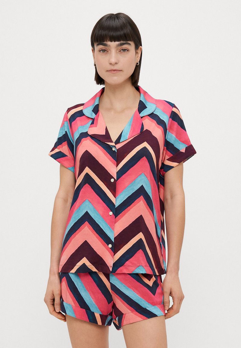 Pajama set s kratkim rukavima u vibrantnom chevron uzorku s ružičastim, plavim i tamnoplavim nijansama. Materijal izgleda lagano s dugmetom za zatvaranje.