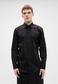 Fekete hosszú ujjú ing klasszikus gallérral, sima anyagból, gombos elöl és testhezálló szabással.