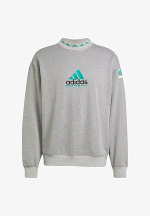 Sudadera gris de tejido suave, con un cuello alto, logotipo de Adidas en turquesa y acentos en contraste en los puños y el collar.