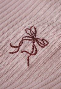 Textilstoff in sanftem Rosa mit gerippter Textur und tiefrotem gesticktem Schleifendetail, das feine Schlaufen und Enden aufweist.