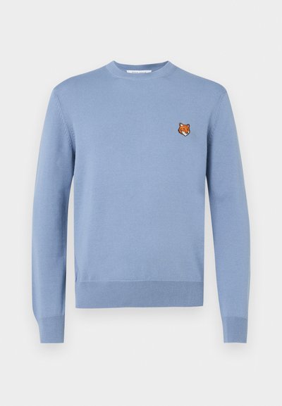 Pulover tricotat de culoare albastru deschis, cu guler rotund, manșete ribbate și o mică broderie cu capul unei vulpi pe pieptul stâng.