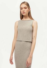 Ljust grå ribbad trikåtop med en boxig passform och vid halsringning. Har subtil textur och kort längd, stylad med en matchande kjol.