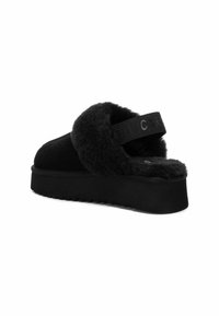 Sandalia negra tipo slide hecha de suave piel de pelo con una suela gruesa. Presenta una tira ancha con una marca en relieve y una suela texturizada para un mejor agarre.