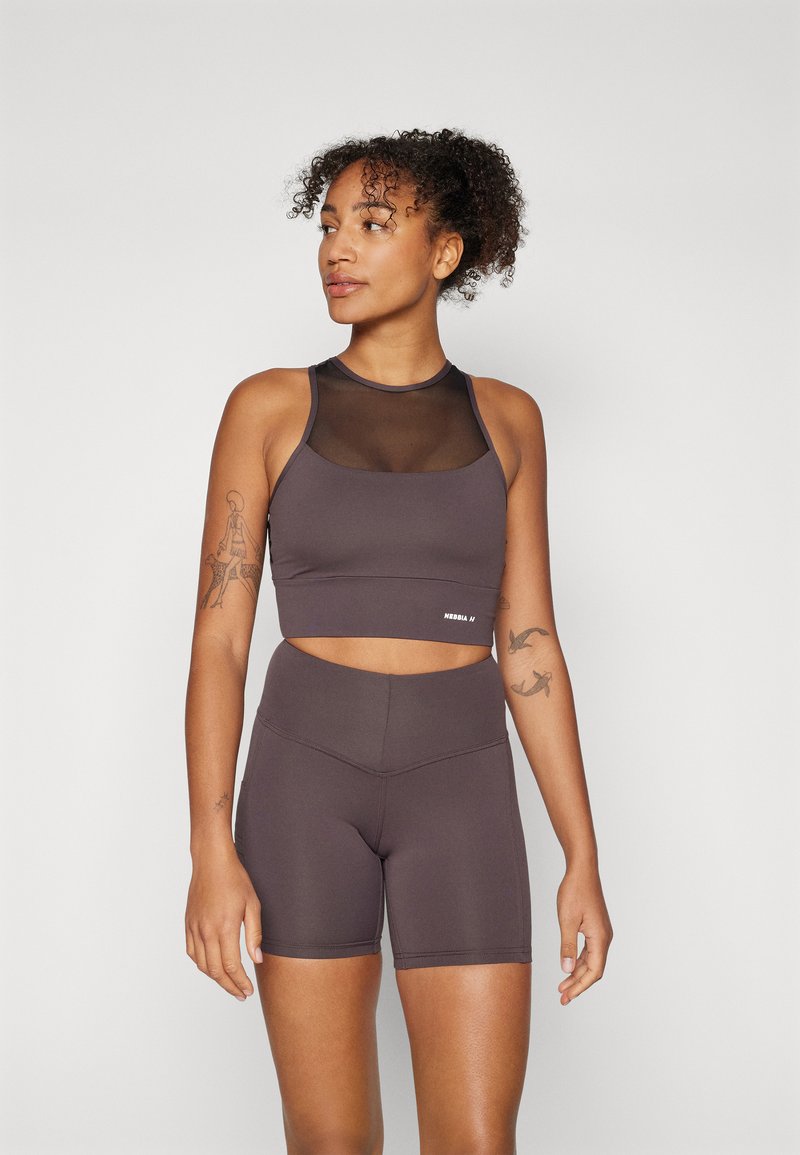 Top cropped de fitness castanho com um painel em rede e calções de cintura alta a condizer, com uma textura suave e um logótipo discreto na bainha.