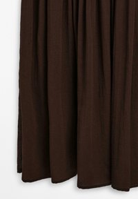 Brauner, leichter Stoffrock mit fließendem Design, der vertikale Falten und einen Saum hat, der knapp über dem Boden endet.