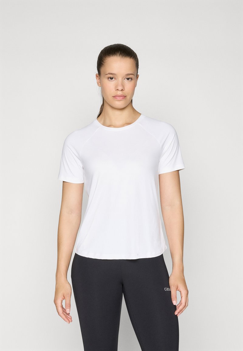 T-shirt bianco a maniche corte in tessuto leggero con colletto rotondo e maniche raglan, abbinato a leggings neri con dettaglio del logo.