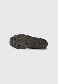 Dark brown shoe sole with zigzag and circular tread patterns, centered on a plain white background.