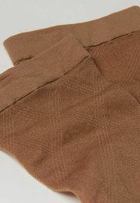 Brune strikkede leggings med en blød tekstur, som har en ribbet talje og et subtilt mønstret design.