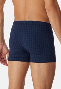 Boxers extensibles à carreaux bleu marine, en tissu doux, avec une taille élastique et une coupe ajustée, ornés de motifs en grille bleus et blancs.