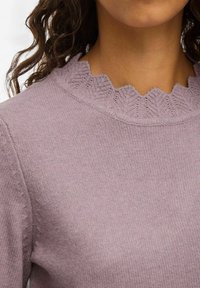 Pull en lilas tricoté avec un col festonné. Texture douce, design ajusté et côtes délicates aux poignets. Pas de motifs ou d'accents visibles.