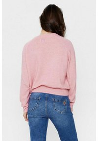 Rosa stickad tröja med rund halsringning, lös passform och ribbad nederkant, kombinerad med blå denimjeans med bakfickor och logodetalj.