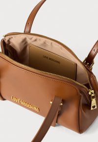 Ταμπά δερμάτινη τσάντα χειρός με χρυσές μεταλλικές λεπτομέρειες, κλείσιμο με φερμουάρ στο πάνω μέρος, διπλές χειρολαβές και εσωτερική θήκη για κάρτες με ανάγλυφο το λογότυπο "LOVE MOSCHINO".