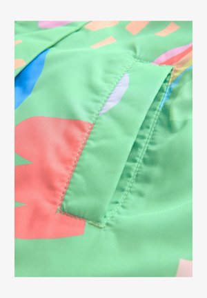 Bunt gemusterter grüner Stoff mit abstrakten rosa, blauen und pfirsichfarbenen Formen, ausgestattet mit einer genähten Tasche und glatter Oberfläche. Sichtbare Nähte.