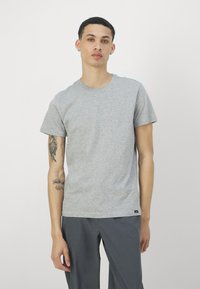 Grå kortermet T-skjorte med klassisk rund hals. Laget av mykt stoff med en glatt tekstur, med et lite logomerke ved kanten.